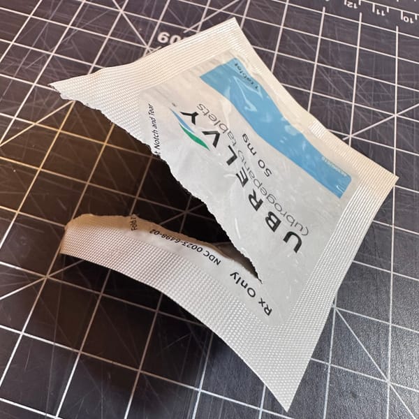 Torn open packet for the migraine medication Ubrelvy on a cutting mat, close up & at a weird angle.